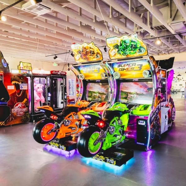 Arcade games at IWingz, including Super Bikes 3, Jurassic Park Arcade, and a claw machine.