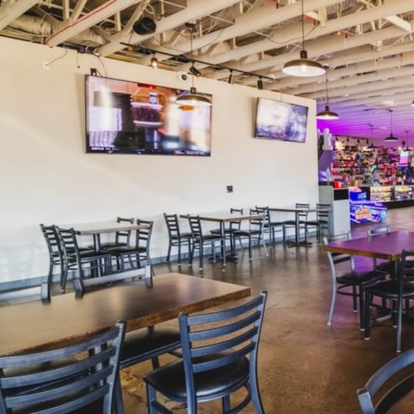 Interior of IWingz restaurant with multiple tables and chairs, TVs on the wall, and arcade games in the back.