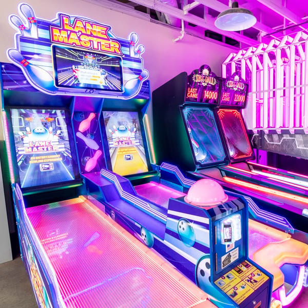 Arcade games at IWingz, including "Lane Master" bowling and Skee-Ball, illuminated by neon lights.